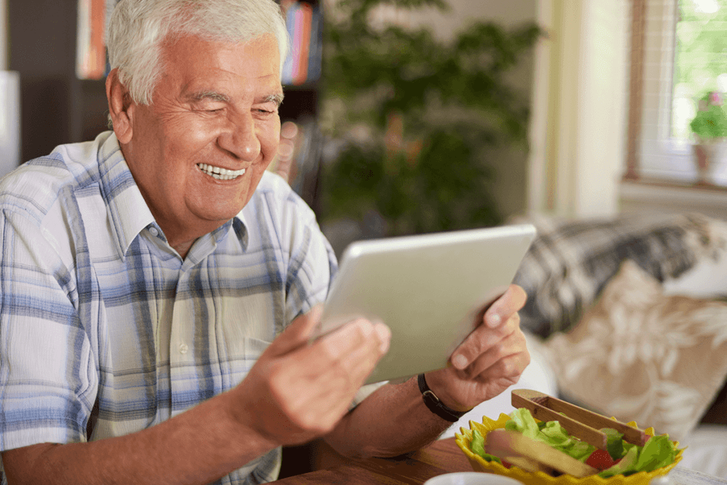 Old man looking at a tab with a happy face